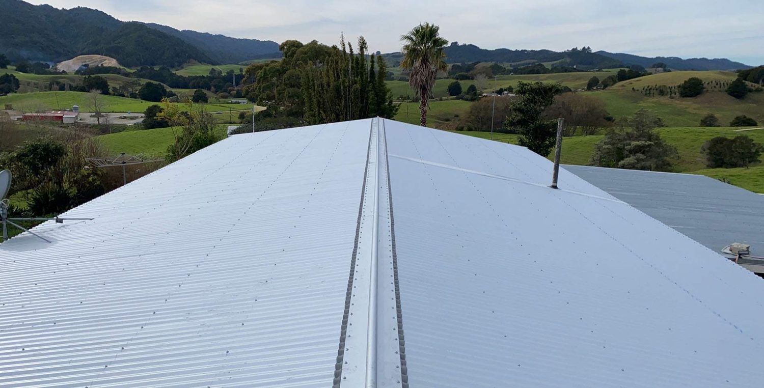 New pale silver corrugated steel roof with ridge capping and a flue, looking out over farmland