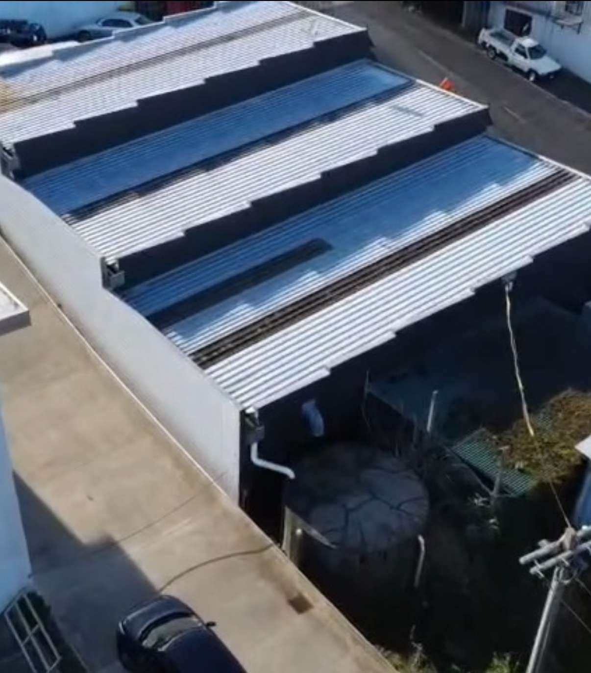 Drone view of a commercial building with a stepped silver steel roof and clear roofing strips