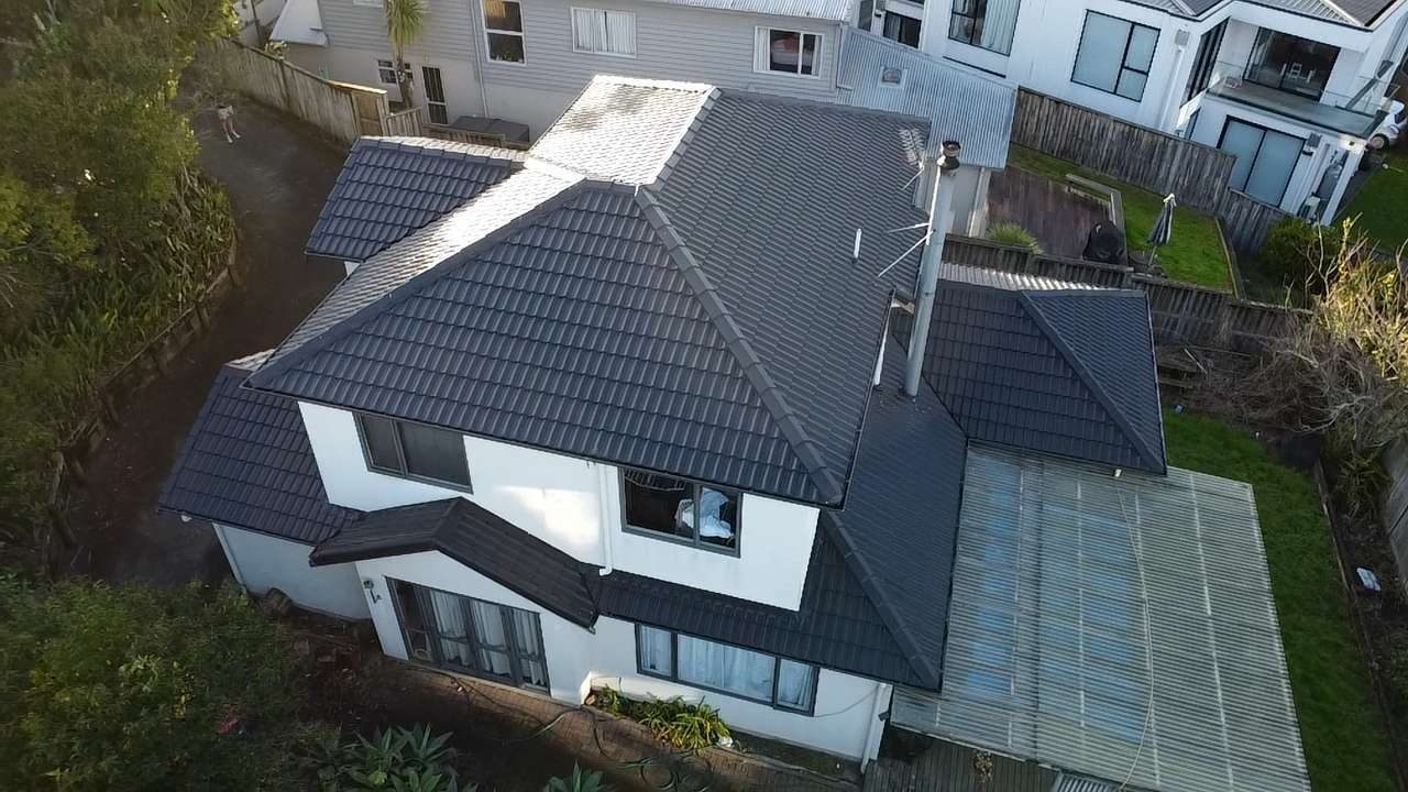 Aerial view of a two-storey white house with a dark tiled hip roof